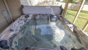 A hot tub with multiple jets, a control panel, and a glass cover. - Home w/Hot Tub -Spacious, Quiet Neighborhood Near Des Moines, IA. (Clive)