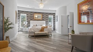 Une chambre à coucher moderne avec un grand lit, un lustre et une vue sur l’extérieur.