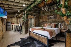 Une chambre rustique avec un lit, un bureau et un téléviseur.