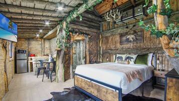 Une chambre à coucher de style rustique, aménagée comme une cabane, avec un lit, un bureau et un réfrigérateur.