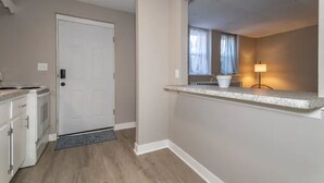 A kitchen with white cabinets, a stove, and a door. - Welcome to the Lakeside Suite! Enjoy! (Fairport Harbor)