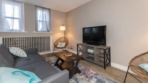A modern living room with a sofa, a coffee table, a TV on a stand, and a chair. - Welcome to the Lakeside Suite! Enjoy! (Fairport Harbor)