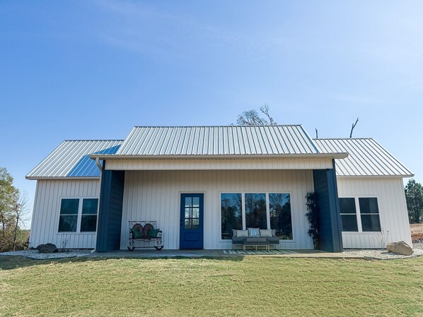 Ein zweistöckiges Haus mit blauer Tür, großen Fenstern und einer Veranda.