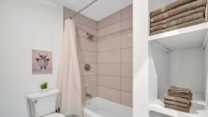 Een badkamer met toilet, douche en planken met handdoeken.