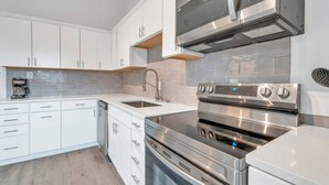 Een moderne keuken met witte kasten, een roestvrijstalen fornuis en een inbouwoven.