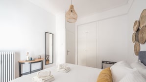 Ein Hotelzimmer mit einem großen Bett, einem Nachttisch mit Lampe, einem Kleiderschrank und einem Spiegel.