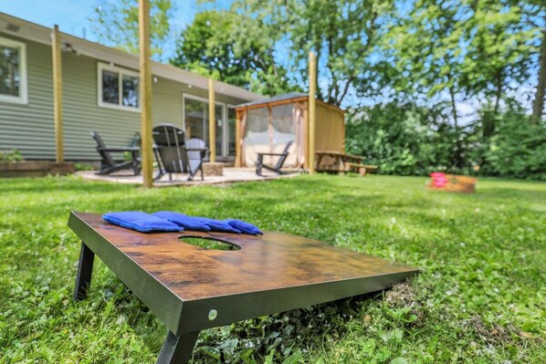 A backyard with a wooden table, a covered seating area, and a house in the background.