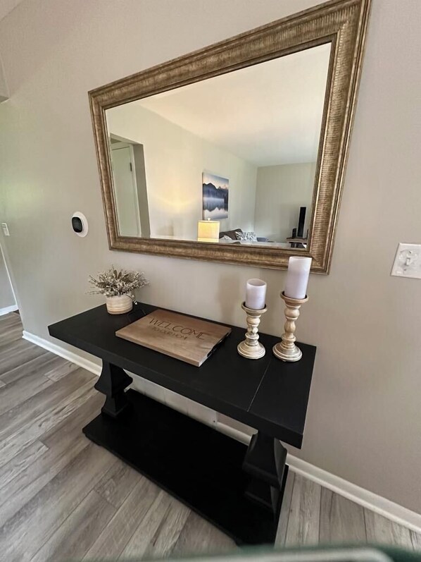 A black console table with a mirror above it, a welcome bag, and two candle holders.