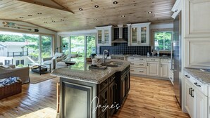 A spacious kitchen with wooden cabinets, a granite countertop, and a large island. - All Day Sun! 7 bed 2 bath cottage on Lake Muskoka! Perfect Location! Privacy! (Torrance)