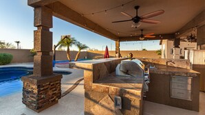 An outdoor patio with a pool, a barbecue grill, and a ceiling fan. - Phoenix Vacation Home -- Pool, Spa, Basketball & Putting Green (Phoenix)