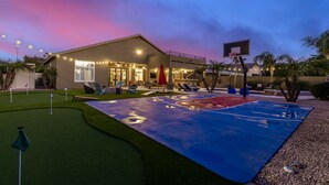 A basketball court with a net, surrounded by a patio area with chairs and a small pool. - Phoenix Vacation Home -- Pool, Spa, Basketball & Putting Green (Phoenix)