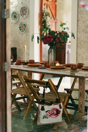 A rustic dining table with a vase of flowers, candles, and traditional pottery. - Xiknal Cozumel (Cozumel)