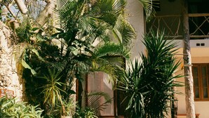 A swimming pool surrounded by lush tropical plants and a building with a thatched roof.