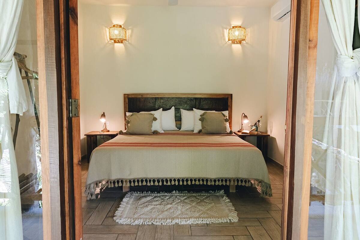 Een slaapkamer met een groot bed, twee bedlampen en een hoofdbord.