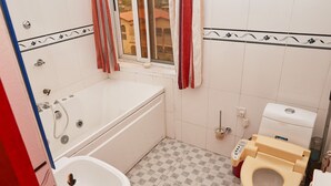 Een badkamer met een bad, toilet en wastafel.