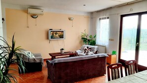 Un salon avec un canapé, une table basse, un téléviseur et une fenêtre donnant sur un beau paysage.