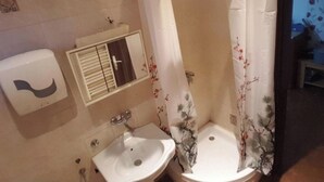 Une salle de bain avec deux lavabos, des toilettes et une douche agrémentée de rideaux à motifs floraux.
