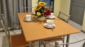 A dining table with four chairs, a vase with flowers, and four white cups and saucers. - Beautiful, central and economical apartment (Rímac)