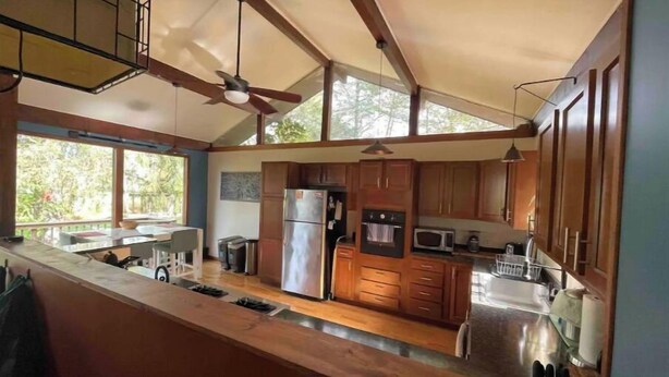 A spacious kitchen with wooden cabinets, a stainless steel refrigerator, and a microwave. - Sweet and spacious mountain view home w/fireplace! (Gardiner)