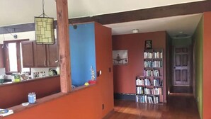 A spacious living area with a wooden floor, a kitchen with wooden cabinets, a bookshelf, and a dining area with a table and chairs. - Sweet and spacious mountain view home w/fireplace! (Gardiner)