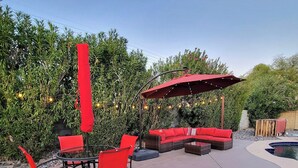 An outdoor patio area with red furniture, a glass table, and string lights. - Spacious 4-bedroom Scottsdale house w/pool, hot tub, billiards in great location (Scottsdale)
