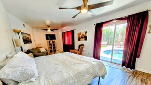 A spacious bedroom with a large bed, a ceiling fan, and a view of an outdoor swimming pool. - Spacious 4-bedroom Scottsdale house w/pool, hot tub, billiards in great location (Scottsdale)