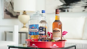 A tray with bottles of Lamoiseau rum and a glass on a table in a room with a white couch and a lamp in the background.