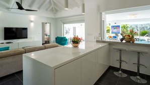 A modern kitchen with a large island, bar stools, and a view of the outdoors.