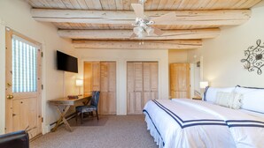 A bedroom with a bed, a desk, a chair, a ceiling fan, and wooden doors. - Charming Santa Fe Adobe Home 2 BR w/Elevated Views (Santa Fe)