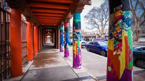 A covered walkway with colorful pillars and a metal fence on the left. - Charming Santa Fe Adobe Home 2 BR w/Elevated Views (Santa Fe)