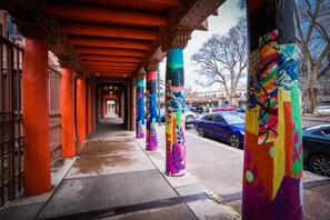 A covered walkway with colorful pillars and a metal fence on the left.