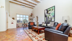 A living room with a sofa, coffee table, and a large abstract painting. - Charming Santa Fe Adobe Home 2 BR w/Elevated Views (Santa Fe)