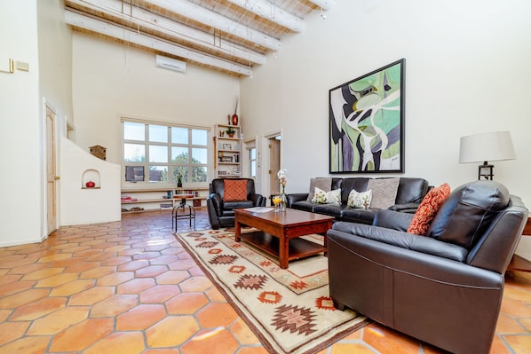 Uma sala de estar com sofá, mesa de centro e uma grande pintura abstrata.