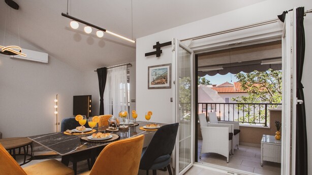A dining area with a table set for two, a view of the outside balcony, and a door leading to the balcony. - A2 - Luxury apt w Terrace, Gym, Jacuzzi & Sauna (Dugi Rat)
