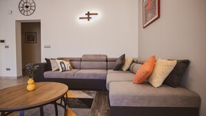 A modern living room with a sectional sofa, a wooden coffee table, and a wall-mounted clock. - A2 - Luxury apt w Terrace, Gym, Jacuzzi & Sauna (Dugi Rat)