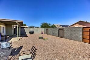 Ein Terrassenbereich im Freien mit Kiesboden, Metallmöbeln und einer Backsteinmauer.