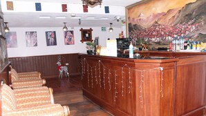 A bar area with wooden furniture, a painting on the wall, and various items on the counter. - Hostal La Catolica (Quito)