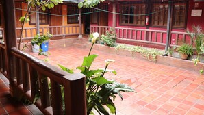 A courtyard with a tiled floor, wooden railings, and potted plants. - Hostal La Catolica (Quito)
