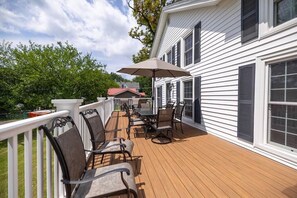 A covered deck with outdoor furniture and a large umbrella. - Cayuga Street Retreat (Lewiston)