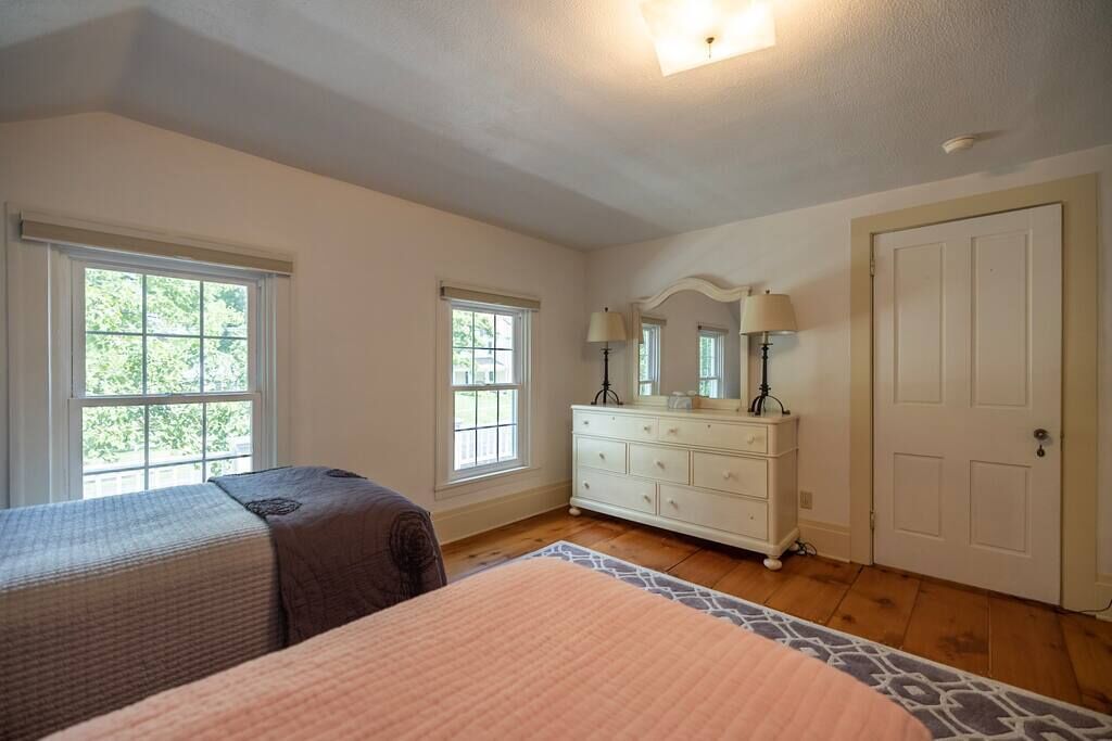 A bedroom with two beds, a dresser, and a door.