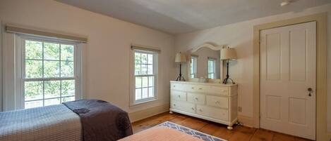 A bedroom with two beds, a dresser, and a door.