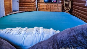 Une chambre de style rustique avec un grand lit, un téléviseur diffusant Netflix et un plafond en bois.