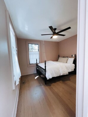 A bedroom with a bed, a ceiling fan, and a window.