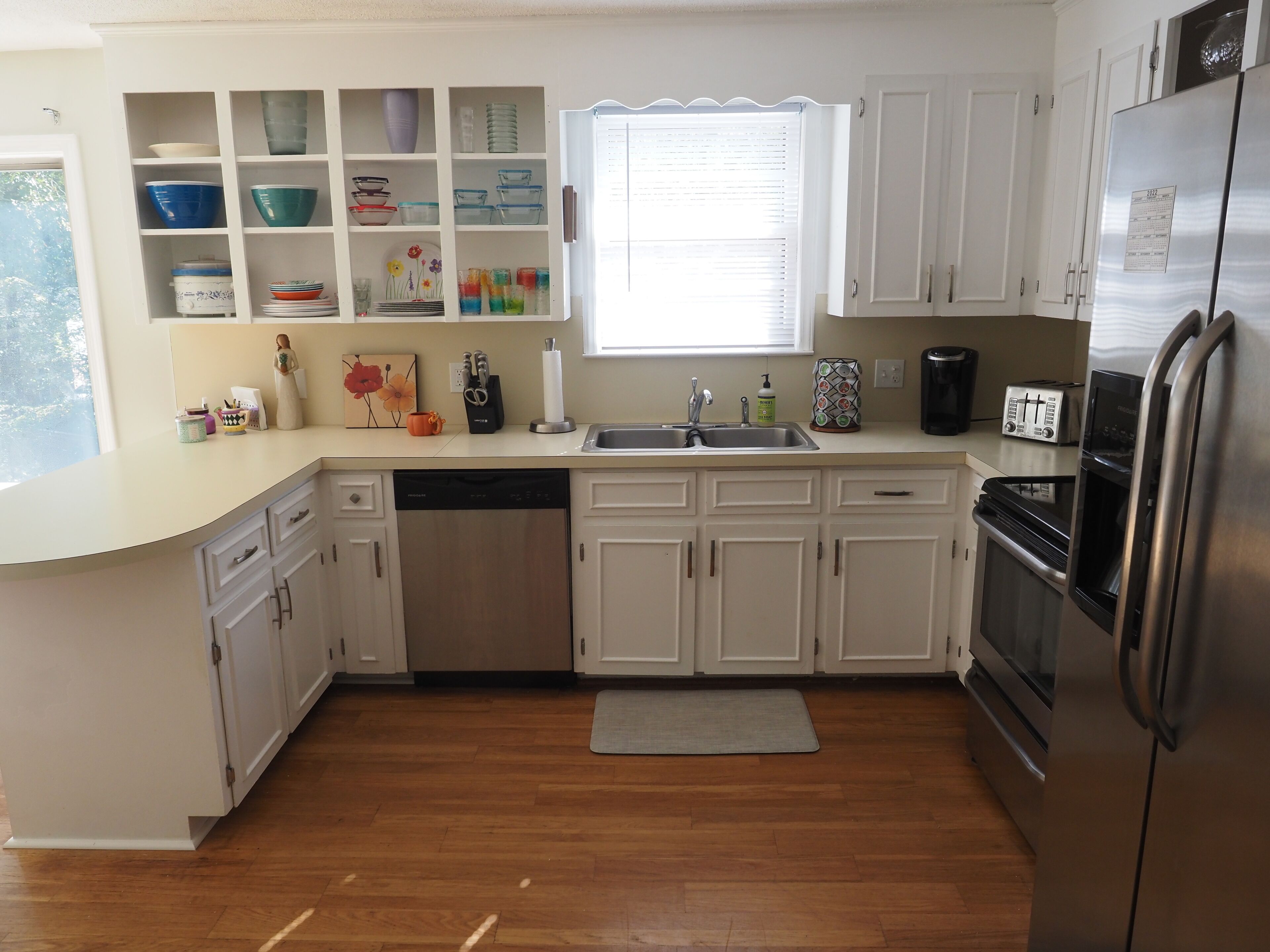 A kitchen with white cabinets, a dishwasher, a refrigerator, and a toaster.