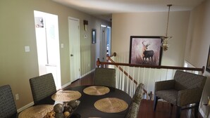 A spacious living room with a high ceiling, a staircase, and a dining area with patterned chairs and a central table. - Homemade in HICKORY! Salt Water Pool!  (Hickory)