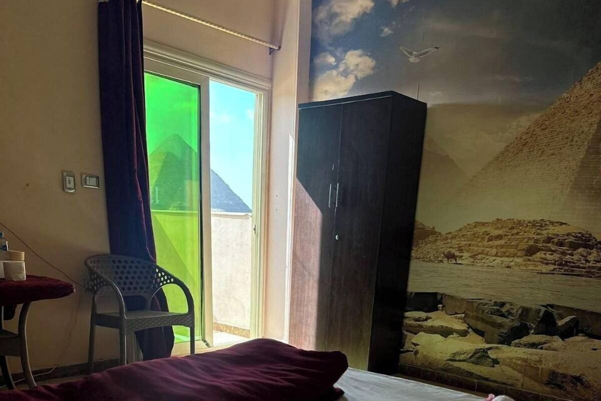 Une chambre d’hôtel avec un lit, un bureau, une chaise et une vue sur un paysage désertique par la fenêtre.