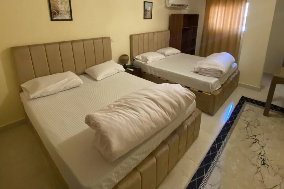 Une chambre d’hôtel avec deux lits, un lustre et un sol carrelé.