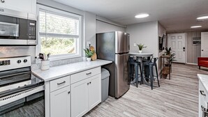 Una cocina moderna con armarios blancos, electrodomésticos de acero inoxidable y una zona de bar con taburetes.