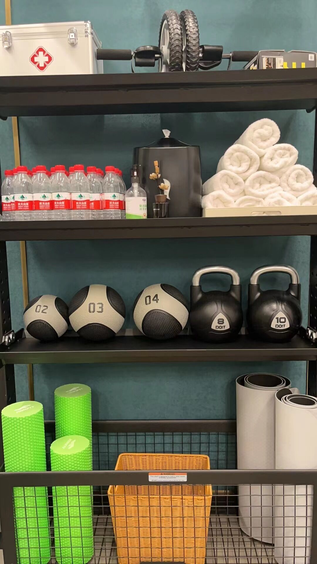 A storage area with shelves containing various items including bottles, towels, exercise equipment, and a basket.