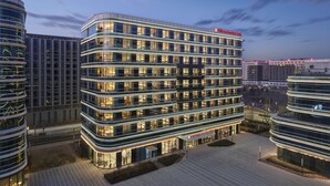 A multi-story hotel with a modern design, featuring a prominent glass facade and illuminated signage.